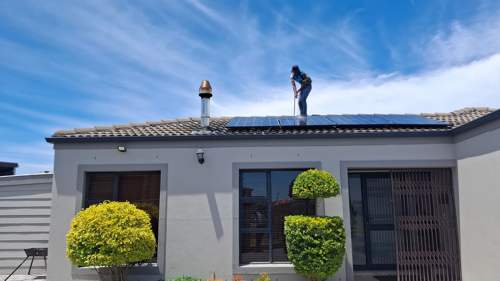 Pose professionnelle sécurisée Installateur posant des panneaux photovoltaïques sur la toiture d’une maison